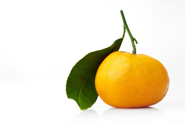 Close up Shot of a Small Orange With Vibrant Texture and Green Leaf Against a Clean White Background