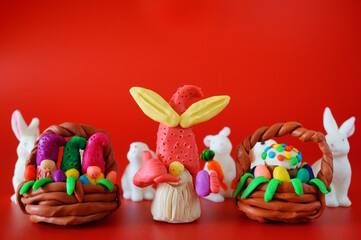 A toy gnome made of plasticine gestures that he is making a phone call. There are rabbit figures and an Easter basket nearby.