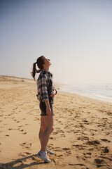 Young woman smiling under sun on beach