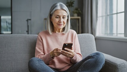 Obraz premium A person sitting on a couch looking at their cell phone, perfect for representing modern life or a scene from a TV show