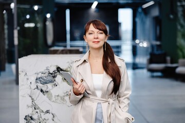 Woman in white coat holding tablet in interior design showroom