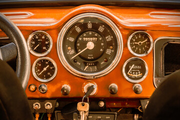 Retro styled image of a dashboard with large speedometer of a British vintage car