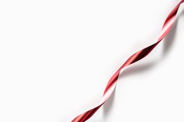 Smooth satin ribbon lying on clean white background. Decorations and embellishments.