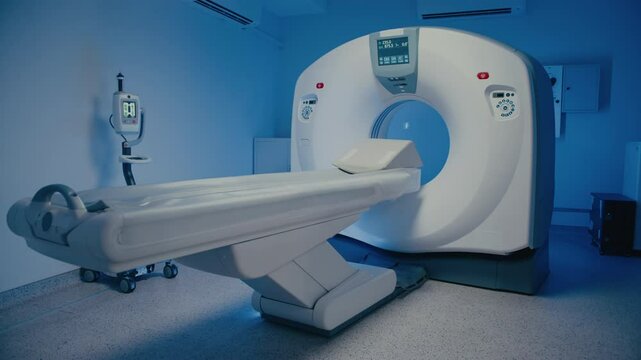 Empty MRI scanner room showing diagnostic machine with extended patient table ready for next procedure. Bright display glowing on device while scanning station remains unused and perfectly prepared.