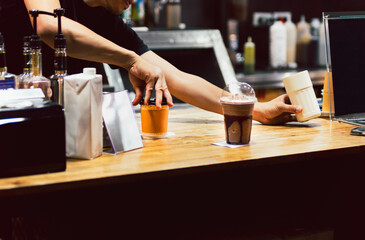 Shot in low light of barista serving a fresh coffee in cafe.