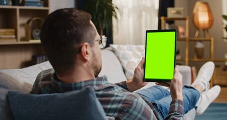 Static back view of Caucasian male with glasses holding tablet device vertically with chroma key on...