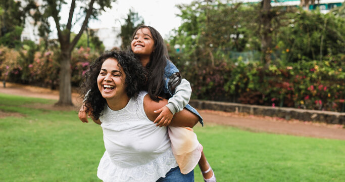 Happy indian mother having fun with her daughter outdoor - Family, mom day and love concept - Soft focus on mum face