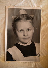 A schoolgirl on old retro photo picture in album.