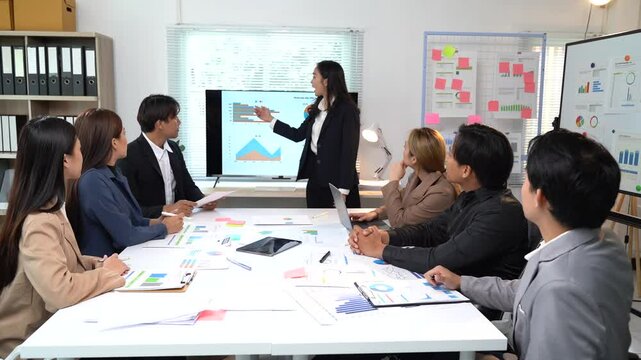 Professional businesswoman using interactive whiteboard presenting marketing data to her colleagues in meeting room, discussing new strategy for company project