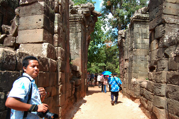 Naklejka premium Tree roots and Ancient ruins antique building Prasat Ta Prohm or Ancestor Brahma temple of Angkor Wat for Cambodian people travelers travel visit respect praying at Angkor Thom in Siem Reap, Cambodia