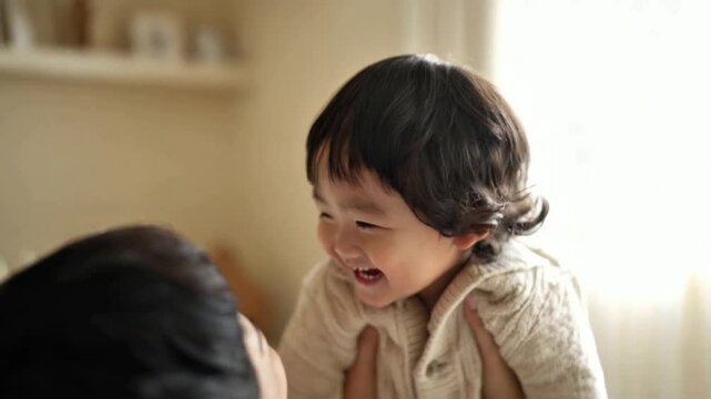 Adorable toddler laughing joyfully while being tickled by a parent