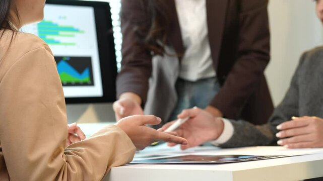 Business team analyzing financial data displayed on a computer screen, actively engaging in discussion and collaboration to make informed decisions