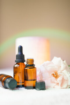 Collection of amber essential oil bottles with fresh rose, diffuser and rainbow light effect