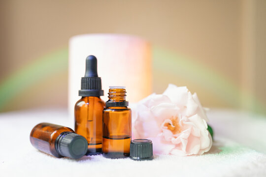 Collection of amber essential oil bottles with fresh rose, diffuser and rainbow light effect