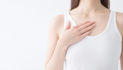 白いタンクトップを着た日本人女性。胸に手を当てている。乳がん検診