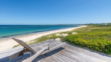 A wooden deck chair near a small sand dune, vibrant blue ocean stretching into the horizon.