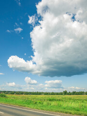 Large cloud is in the sky above a field