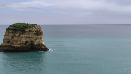 Naklejka premium Aerial footage of a hidden paradise featuring a rock formation island. Captured 04/04/2025 in Portimao, Portugal