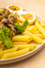 Delicious breakfast, pasta with fried mushrooms and broccoli, green peas and corn, fresh mix salad with radishes with seeds