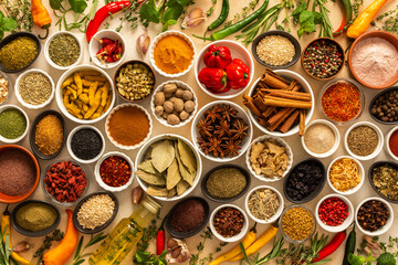 Diverse selection of cooking spices and dried herbs on a beige background, showcasing natural textures and colors that enhance culinary experiences