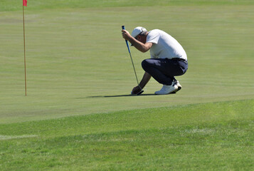 Golfer on the green placing the ball in the correct position to try to make the last shot for the...
