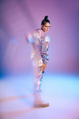 Stylish woman showcases vibrant holographic fashion in a modern setting at twilight