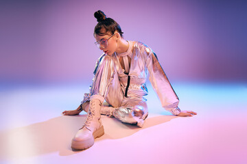 Stylish woman showcases vibrant holographic fashion in a futuristic urban setting
