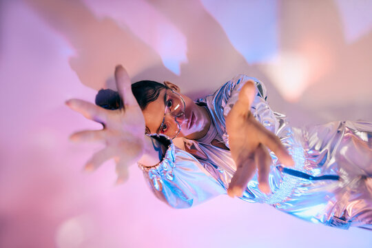 Stylish woman in holographic attire embraces futuristic fashion in a vibrant setting - Powered by Adobe