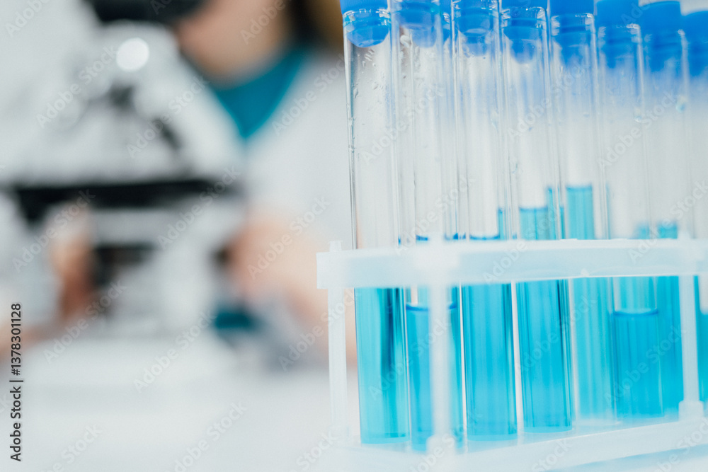 Poster A closeup shot of a rack filled with test tubes containing blue liquid, highlighting the precision and focus of laboratory experiments. blurred background suggests scientist working with a microscope