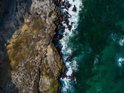top down coastal view of ocean waves crashing onto rocks on the Australian coast