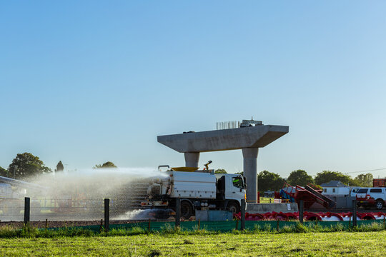 Water spraying truck dampening down ground to minimize dust on construction site