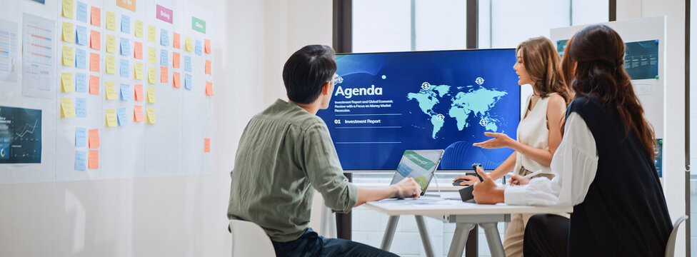 Group of Asian generation z business people work together in home office. Financial team businesspeople brainstorm meeting, use laptop computer and presentation screen. Corporate teamwork concept