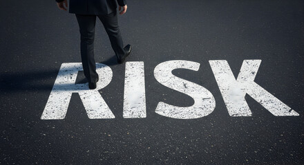 Rear View Of Businessman Walking On Asphalt With White Risk Text Painted On Ground