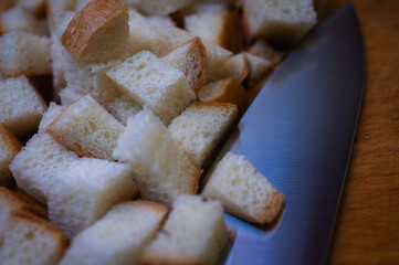 Golden brown croutons, sliced ​​bread and knife on wooden surface, create a delicious texture and crunch. Perfect close-up of bread cubes for cooking, recipes or food background