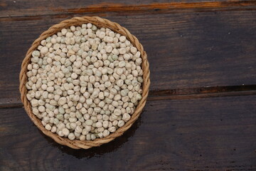 wicker basket with pea seeds for sowing in the vegetable garden with wood bottom