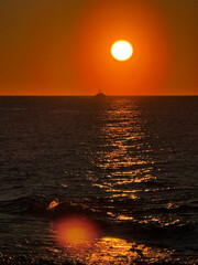 Sunset over ocean with a boat and shimmering golden water
