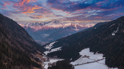 Aerial view of a snow covered valley in the Dolomites, Italy, with forested mountains, a small...