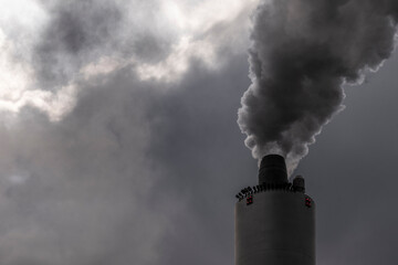 Close-up of factory smokestack with dark emissions. Pollution and climate change concept in minimal industrial scene with moody atmosphere.