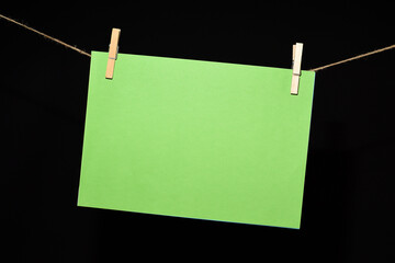 Cartulina verde colgada con pinzas sobre fondo negro