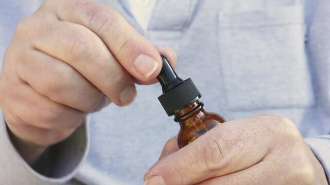 Preparing to Treat Fungal Nail Infection - Man Opens Antifungal Ointment Bottle, Squeeze Rubber Teat to Fill Glass Dropper