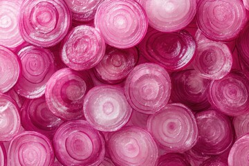 Close-up view of many thinly sliced red onions, arranged in overlapping circles.  A vibrant display of the vegetable's layers and colors