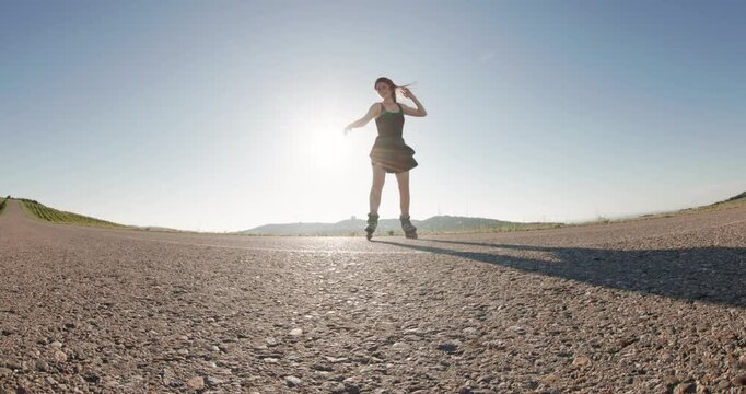 Sporty woman riding on roller skates outdoor on road, wide angle shot