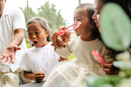 Happy Asian family making soap bubbles outdoors