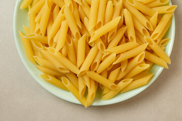 Bright yellow pasta arranged neatly on a green plate ready for cooking