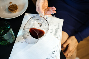 Wine glass tilted over tasting notes at a fine dining table. Curated experiences, sensory design, sommelier culture