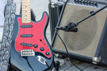 Close-up of an electric guitar leaning against a vintage amplifier with a microphone in front. Live...
