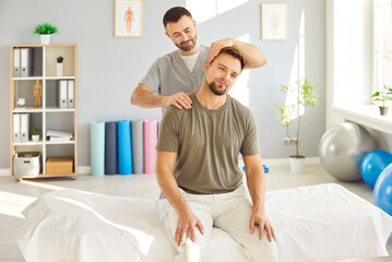 Professional chiropractor, osteopath or physiotherapist helping get rid of neck pain to young man...