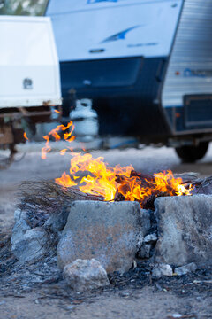 flames of campfire in foreground with caravan in background