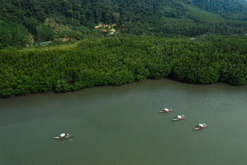 Many ancient wooden boats with rowers are traveling on the river and green forest.Nature boating, nature tourism © Warut