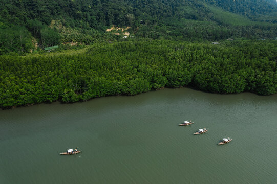 Many ancient wooden boats with rowers are traveling on the river and green forest.Nature boating, nature tourism